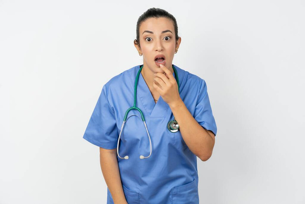 青い制服を着た神経質なアラブの医師の女性は驚きから口を開き,突然のニュースに反応します. - 写真・画像