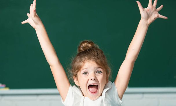 Excited school girl face with surprising expression against blackboard - Фото, изображение