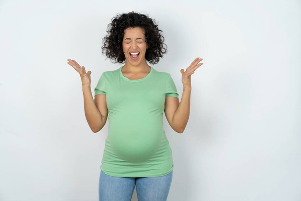 Τρελή εξοργισμένη έγκυος γυναίκα φωνάζει δυνατά και χειρονομίες θυμωμένα φωνάζει μανιωδώς. Έννοια των αρνητικών συναισθημάτων - Φωτογραφία, εικόνα