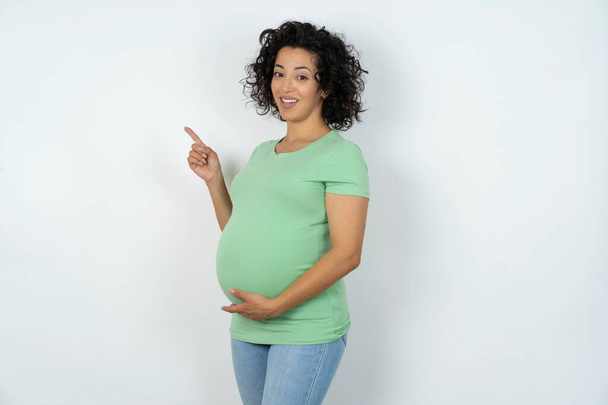 έγκυος γυναίκα δείχνει στην άκρη αντίγραφο κενό χώρο. Έννοια της προώθησης και της διαφήμισης - Φωτογραφία, εικόνα