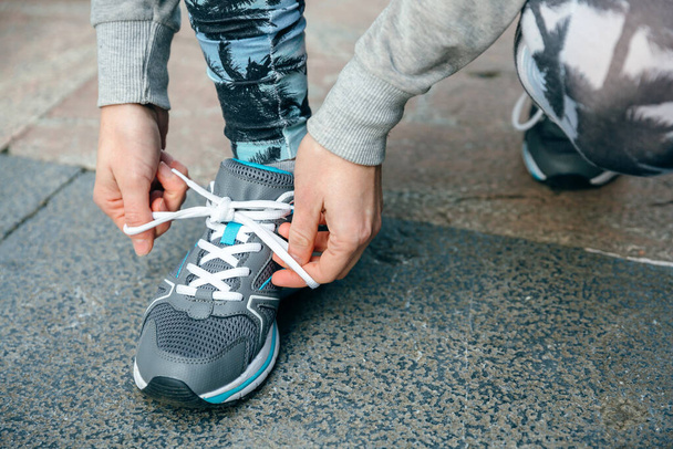 Close up of unrecognizable woman runner tying her sneakers laces to training on town - Fotografie, Obrázek