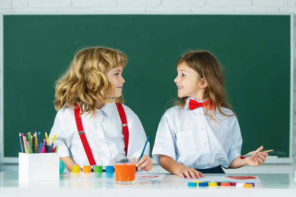 Children doing school lesson at class. Funny school girl an boy pupil drawing a picture. Cute little preschoolers drawing at school. School friends - Foto, Bild