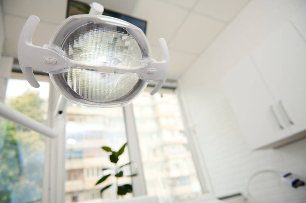 Attrezzature dentali. Una lampada dentale con luce LED direzionale all'interno bianco chiaro di una moderna clinica odontoiatrica. Lampada operativa. Lampada chirurgica. Assistenza sanitaria e medicina. Copia spazio pubblicitario - Foto, immagini