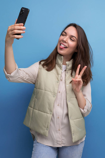 brunetka młoda kobieta biorąc selfie za pomocą telefon komórkowy na studio tle. - Zdjęcie, obraz