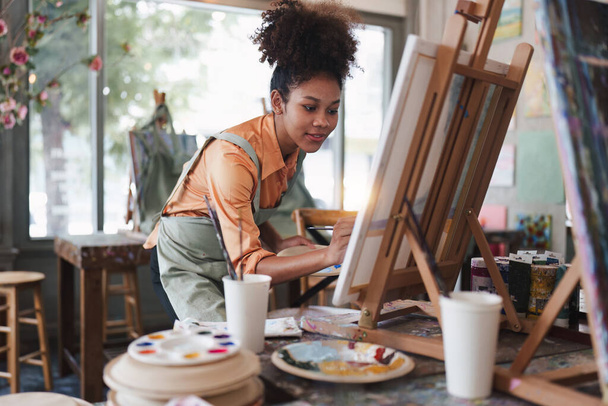 Bella artista americana africana pittura donna in studio d'arte presso l'aula universitaria. - Foto, immagini