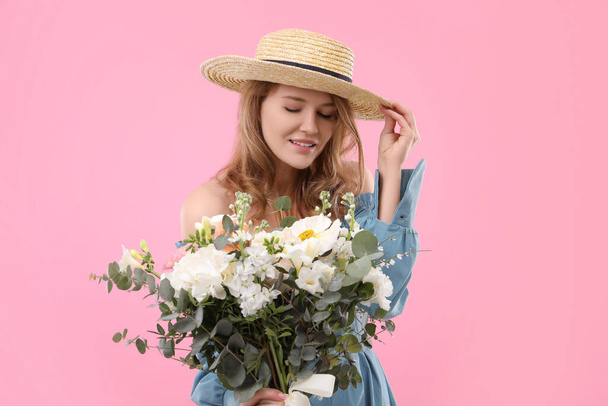 Beautiful woman in straw hat with bouquet of flowers on pink background - Fotografie, Obrázek