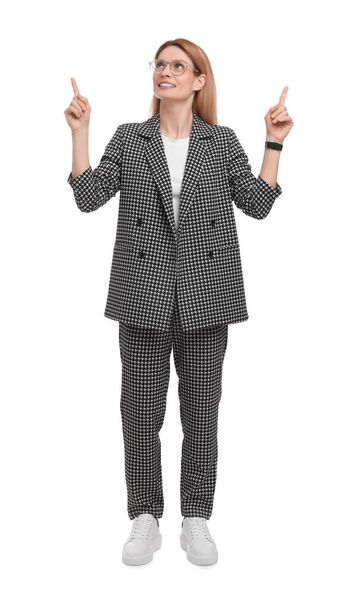 Beautiful happy businesswoman in suit pointing at something on white background - Фото, изображение
