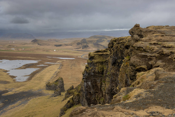 Paese sulla costa dell'oceano Atlantico. Piccolo lago circondato da montagne ricoperte di muschio e licheni in autunno. Cielo nuvoloso. Dyrholaey, Islanda meridionale. - Foto, immagini