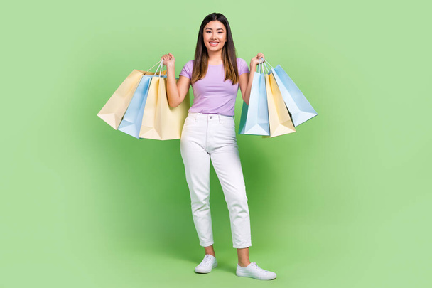Full length body photo of vietnamese woman hold her shopping bags big clothes outlet nike store isolated on green color background. - Fotoğraf, Görsel