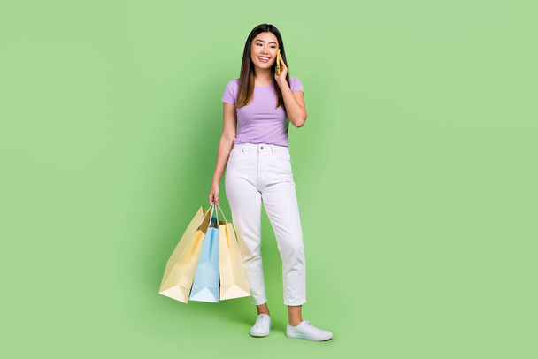Full length body photo of young attractive japanese girl call friends announce last chance sale isolated on green color background. - Fotó, kép