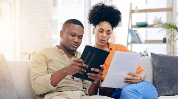 Black couple,tablet, documents and financial crisis on living room sofa discussing mortgage payment or loan at home. Frustrated African man and woman with paperwork in debt, finance issue or money pr. - Photo, Image