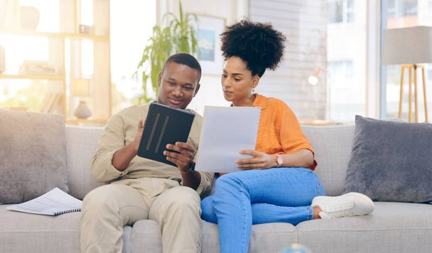 Tablet,documents, smile and couple on sofa in home living room, bonding and online shopping. Interracial, technology and happy black man and woman relax on social media, internet browsing or web scro. - Foto, Imagen