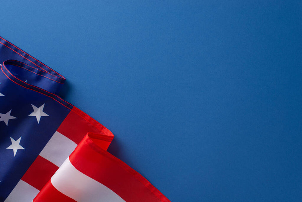 Concepto de fiesta federal estadounidense. Foto de alta vista angular de la bandera de Estados Unidos de América en la esquina izquierda sobre fondo azul aislado con espacio de copia - Foto, imagen