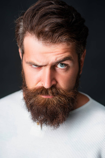 Portrait of stylish handsome young man with beard standing on black wall - Photo, image