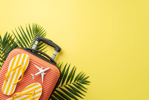 Відпустка вібрує. Вид зверху на помаранчеву валізу, пляжні аксесуари, фліп-флоп та зелене пальмове листя на жовтому тлі з порожнім місцем для тексту або реклами
 - Фото, зображення