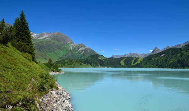 Reservoir lake with mountains epic landscape. Idyllic reservoir Kops lake at 1800 m in austrian Galtur, Vorarlberg - 写真・画像
