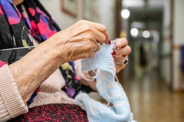Пожилая женщина вяжет крючком на курсах рукоделия в качестве хобби или трудотерапии в доме престарелых. Высокое качество фото - Фото, изображение