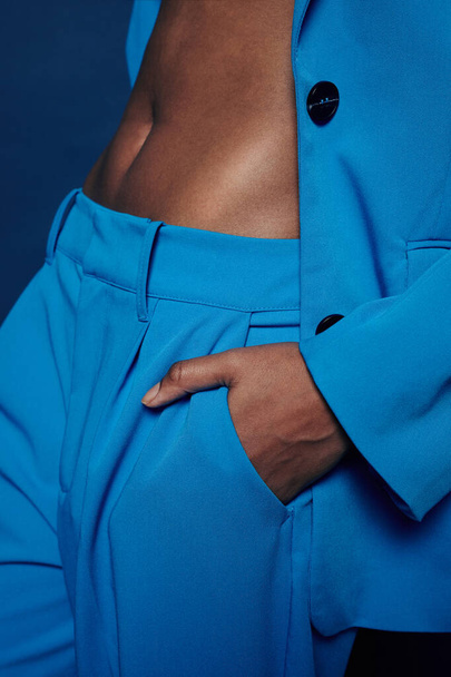 Minimaal detail van jonge zwarte vrouw met fit figuur in levendig blauw broekpak en vibing - Foto, afbeelding