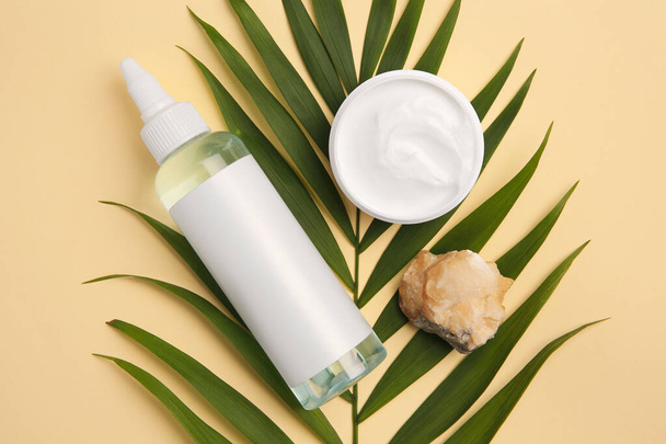 Cosmetic products, palm leaf and quartz gemstone on beige background, flat lay - Фото, зображення