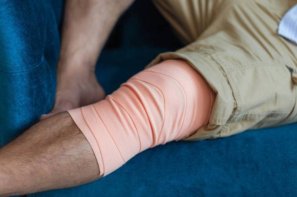 Detailní záběr na mužovu nohu obalenou obvazem. Zranění z nehody. Koncepce svalového napětí - Fotografie, Obrázek