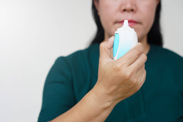 Close-up vrouw hand houdt neusspray suspensie voor gebruik met de neus. Farmaceutische producten voor behandelingssymptomen van allergische rhinitis. Voorgeschreven gebruik.  - Foto, afbeelding