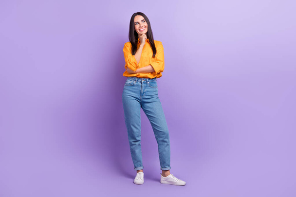 Full length photo of satisfied minded good mood girl dressed yellow shirt pants look at empty space isolated on purple color background. - Фото, зображення