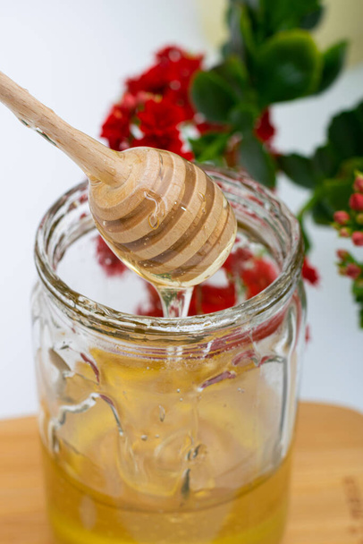 Colher de madeira com mel de abelha em frasco de vidro - Foto, Imagem