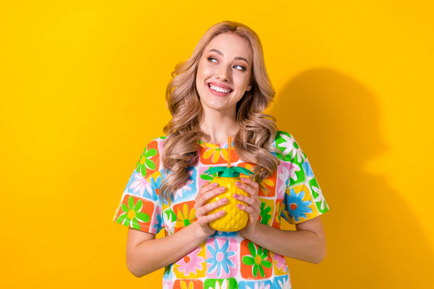 Portrait of optimistic cute woman wear flower print t-shirt holding pineapple mug look empty space isolated on yellow color background. - Zdjęcie, obraz