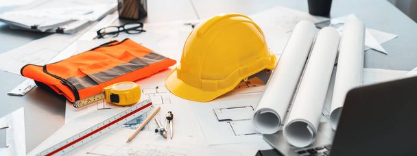 Architectural designed building blueprint layout and engineer tool for designing blueprint with contractor project document on engineer workspace table in office with safety helmet or hardhat. Insight - Photo, image