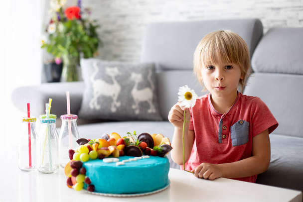 Cute preschool boy with birthday cake with candles at home, preparing for party with friends and siblings - Foto, imagen