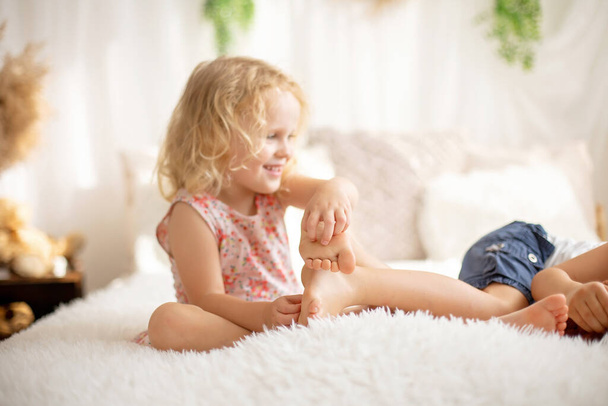 Cute sweet toddler children, tickling feet on the bed, laughing and smiling, childish mischief, happiness - Foto, Imagen