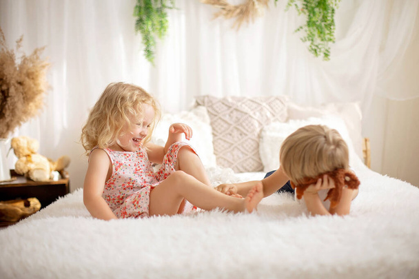 Cute sweet toddler children, tickling feet on the bed, laughing and smiling, childish mischief, happiness - Foto, Bild