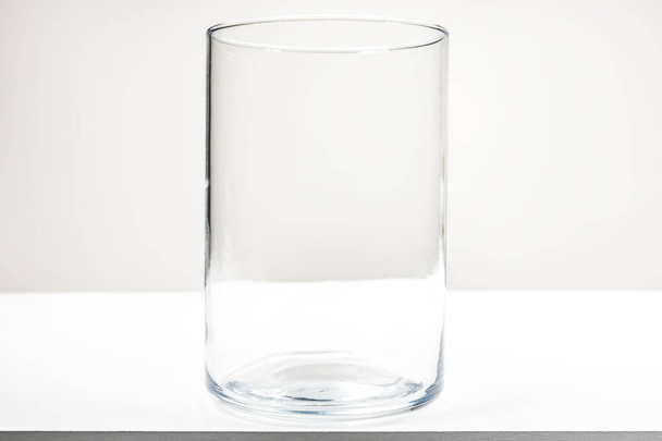 Um grande frasco de vidro vazio sem tampa sobre uma mesa de madeira branca - Foto, Imagem