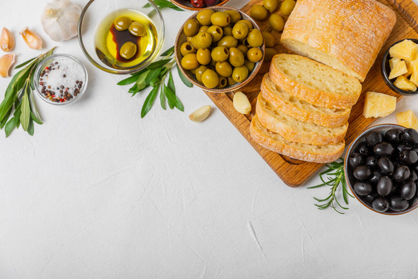 Italian ciabatta bread with olives, garlic, parmesan and rosemary on a light concrete background. Tasty food. Aperitif. Place for text. copy space. Delicacy. Bon appetit. - Photo, image