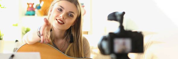 Músico femenino grabando videos de enseñanza de guitarra. Cantando y tocando la blogger femenina en la guitarra delante de la cámara - Foto, imagen