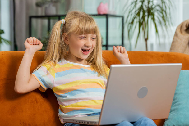 Şaşırmış küçük kız çocuğu dizüstü bilgisayar kullanıyor, iyi haber mesajı alıyor, ani zaferle şok oluyor, oyun zaferini kutluyor, piyango ikramiyesi kazanıyor, evden online alışveriş yapıyor. Yaşam Tarzları - Fotoğraf, Görsel