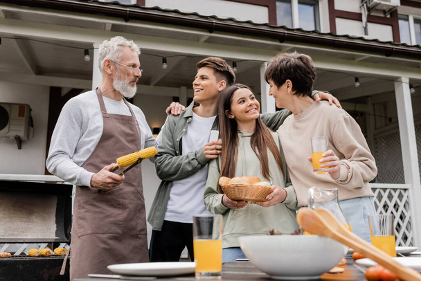 parents day, celebration, happy middle aged parents having bbq party with teenage daughter and young adult son, father holding tongs with grilled corn, summer house, suburban life, june  - Fotoğraf, Görsel