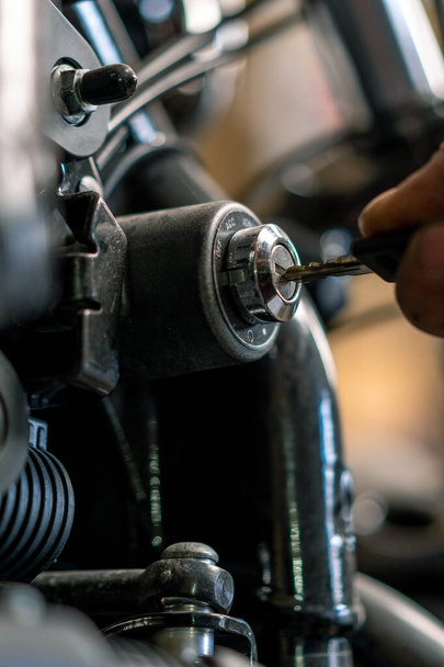 Креативна автентична мотоциклетна майстерня Байкер-механік в гаражі введення ключа в коробку живлення, щоб почати мотоцикл крупним планом - Фото, зображення
