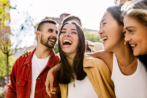 Monipuolinen ryhmä nuoria ystäviä pitää hauskaa ulkona kesällä. Millennial opiskelija ihmiset nauravat kävely kaupungin kadulla nauttia vapaapäivästä. Nuorisoyhteisön ja ystävyyden käsite. - Valokuva, kuva