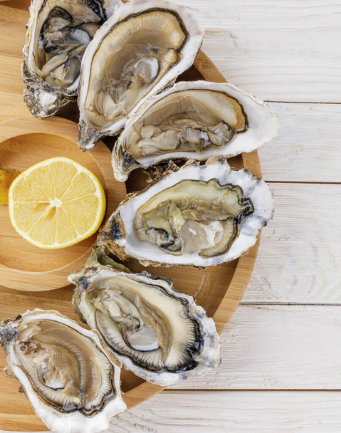 oysters with lemon on a light wooden table - Photo, Image