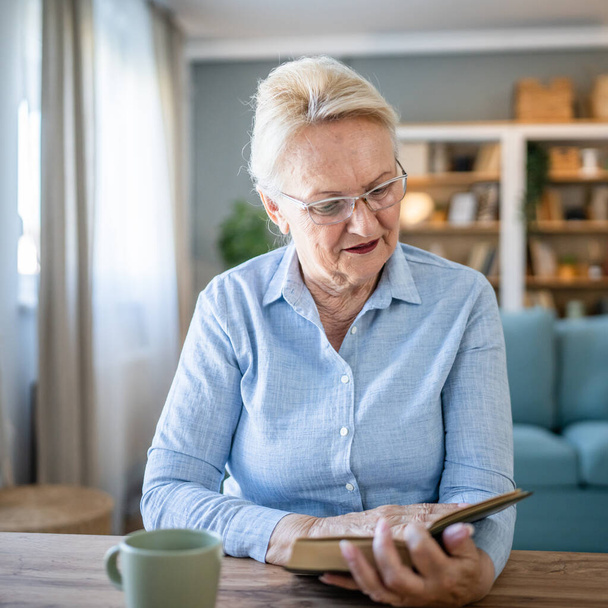 Одна женщина взрослая старшая белая пенсионерка современная бабушка читала книгу на дому в очках реального человека копировать пространство - Фото, изображение
