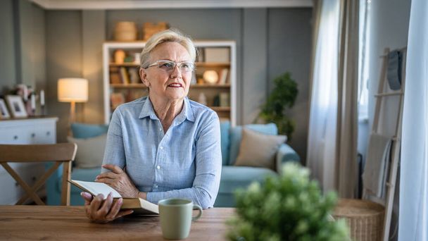 One woman mature senior caucasian female pensioner modern grandmother read book at home wear eyeglasses real person copy space - Foto, Imagem