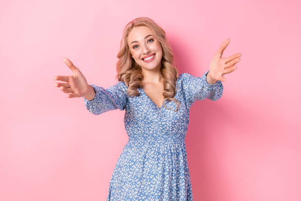Photo of young good mood girl blonde curly hair wear blue flower print dress hands inviting missing you isolated on pink color background. - Fotoğraf, Görsel