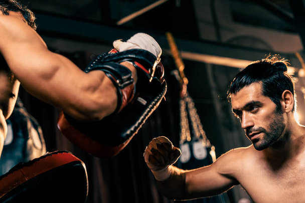 Azjatycki i kaukaski bokser Muay Thai uwalnia cios w zaciętej sesji treningowej boksu, dostarczając cios bokserski sparingowi trenerowi, pokazując technikę i umiejętności boksu Muay Thai. Impetus - Zdjęcie, obraz