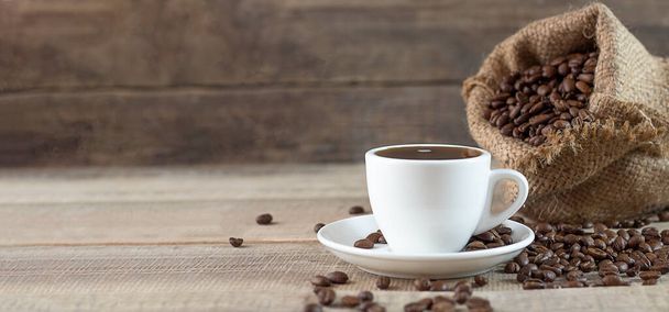 Eine Tasse Kaffee. Kaffeebohnen auf einem hölzernen Hintergrund. Kopierraum. Banner - Foto, Bild