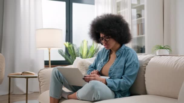 Sokkolt afro-amerikai nő negatív rossz érzelem szomorú ideges aggódó zavaros reakció laptop értesítés bank elutasítja üzleti kudarc tanulmányozása elveszett lány sokk számítógép probléma otthon kanapé - Felvétel, videó