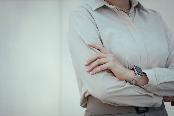 Oficina para mujer o estilo de negocio en ropa. Imagen femenina restringida en tonos beige con un reloj inteligente. - Foto, Imagen