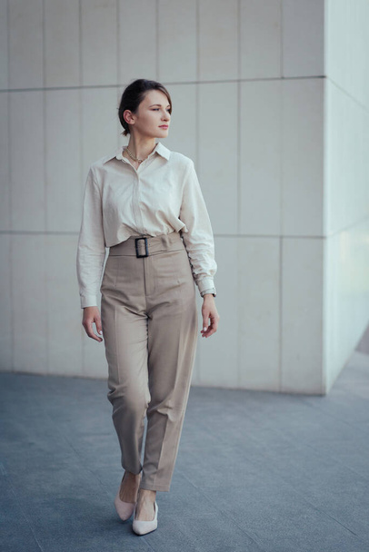 Young caucasian model woman in office or business fashion style pantsuit in beige tones, vertical. - Фото, изображение
