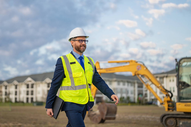 Architect at a construction site. Architect man in suit and helmet at construction site. Confident architect standing at construction. Investor or civil engineer. Outdoor portrait of hispanic - Photo, image
