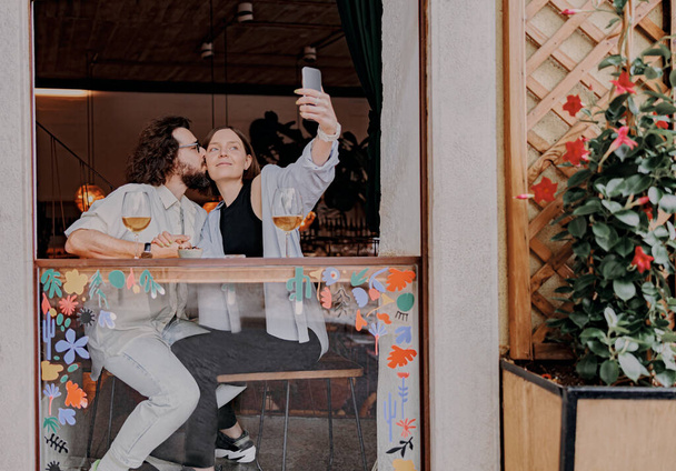 Couple kissing and take a selfie while drinking wine in bar during romantic date. High quality photo - Photo, image